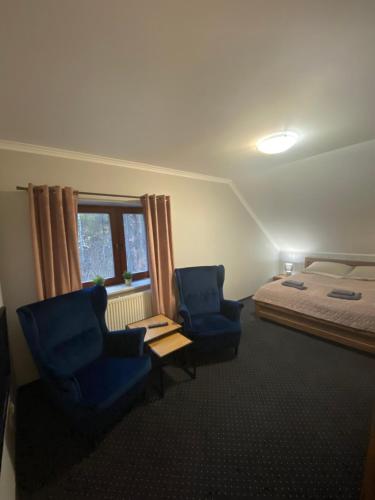 a bedroom with two blue chairs and a bed at Restauracja Zacisze Leśne Noclegi in Knurów