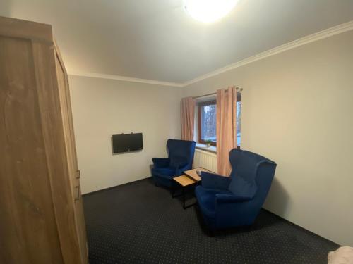 a room with two blue chairs and a table and a television at Restauracja Zacisze Leśne Noclegi in Knurów