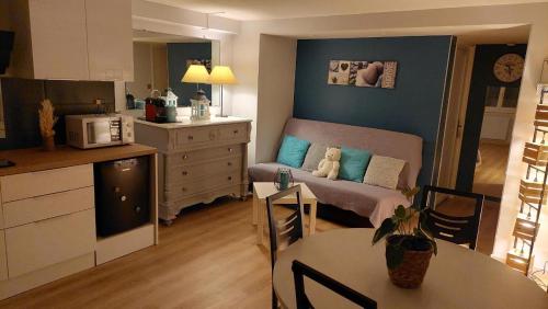 a kitchen and a living room with a couch and a table at Ma maison fleurie proche AEROPORT LYON ST EXUPERY, LDLC ARENA, Groupama Stadium,Eurexpo in Janneyrias