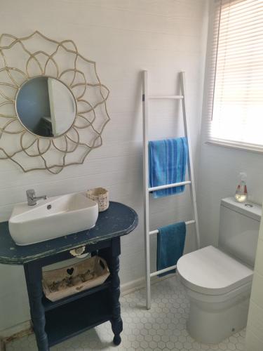 a bathroom with a sink and a toilet and a mirror at Whispering waves in Gamtoosriviermond