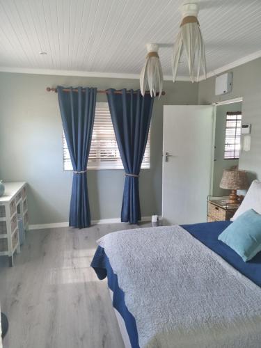 a bedroom with blue curtains and a bed at Whispering waves in Gamtoosriviermond