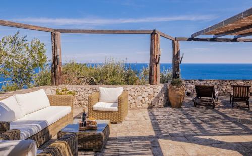 CorsanoにあるVilla Méditerranée Luxury Sea Viewの石壁のパティオ(ソファ、椅子付)