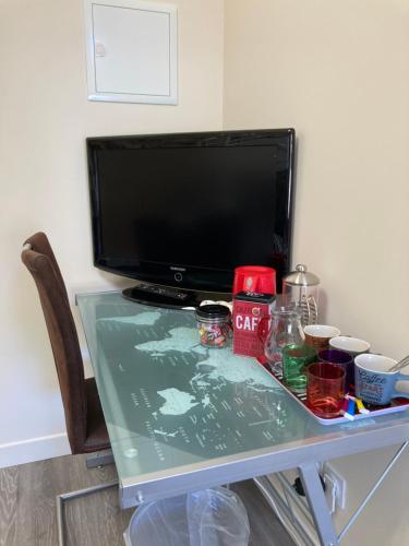 escritorio con TV y mesa con encimera de cristal en La Chambre du Tonneau, en Montigny-sur-lʼAin