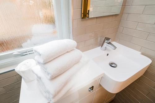 Low Moor Lodge في سكرابورو: حمام مع حوض أبيض ومرآة