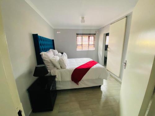 a bedroom with a white bed with a red blanket at The Curve Apartments Unit 3 in Johannesburg