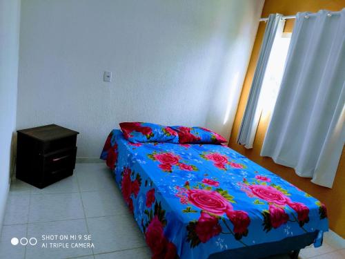 1 dormitorio con 1 cama con edredón azul con rosas en Aconchegante casa de praia em Paripueira/AL, en Paripueira