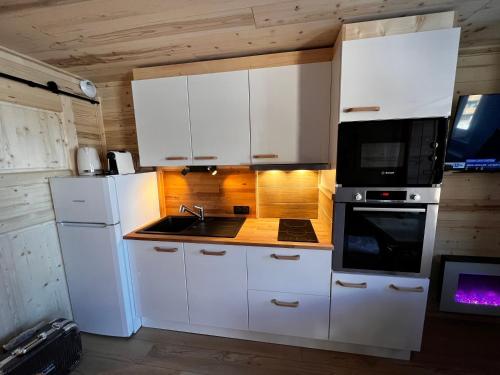a kitchen with white cabinets and a sink and a microwave at Les appartements de Makalu Val Thorens in Val Thorens