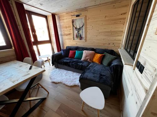 a living room with a black couch in a tiny house at Les appartements Makalu Val Thorens in Val Thorens