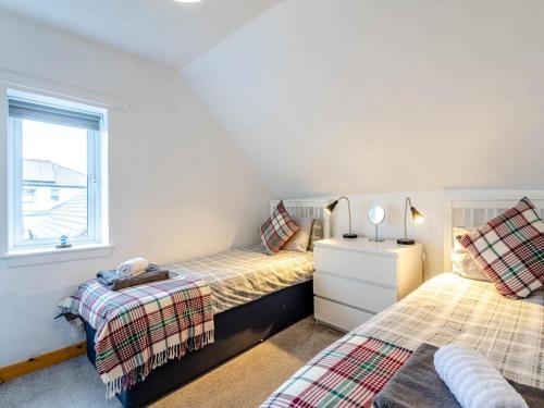 a twin bedroom with two beds and a window at Cosy 3 bedroom home in centre of Brodick in Brodick