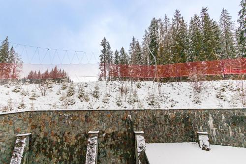 a fence covered in snow with trees in the background at Petros Hotel in Bukovel