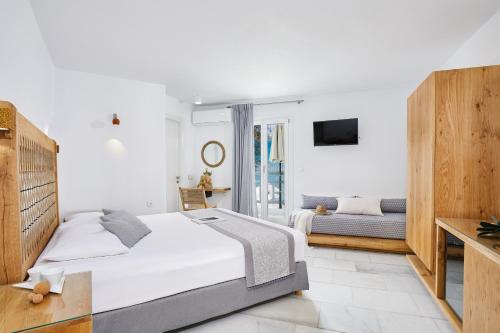 a white bedroom with a bed and a couch at Kalergis Studios in Naxos Chora