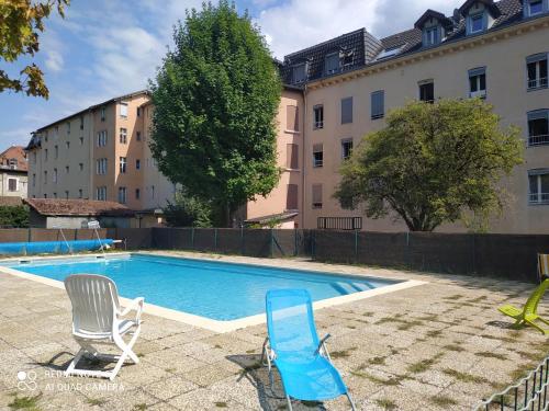 une piscine avec deux chaises et un bâtiment dans l'établissement Joli studio au centre d'Uriage, à Vaulnaveys-le-Haut
