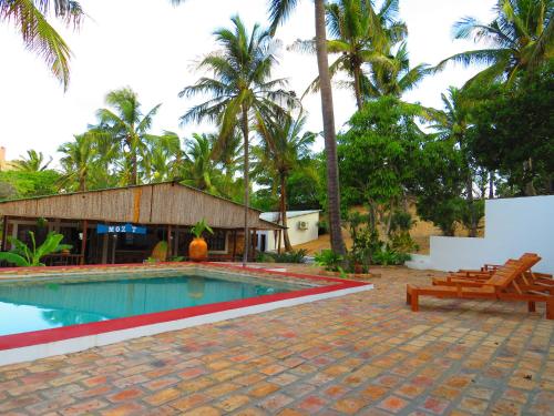 a swimming pool in a resort with palm trees at Moz T's Lodge in Inhambane