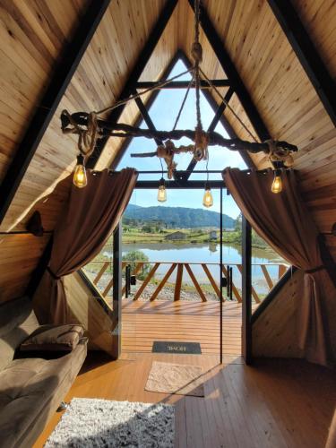 a room in a tree house with a large window at Chalé Encanto Do Lago in Urubici