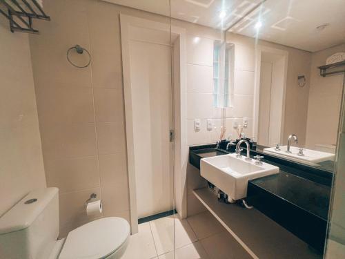 a bathroom with a white toilet and a sink at Apto conforto extremo no melhor do Centro de CWB in Curitiba