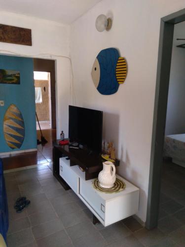 sala de estar con TV de pantalla plana en la pared en Casa dos passarinhos, en Arraial do Cabo