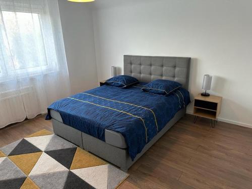 Schlafzimmer mit einem Bett mit blauer Decke in der Unterkunft Vaste appartement cosy avec parking gratuit et espace de travail in Illkirch-Graffenstaden