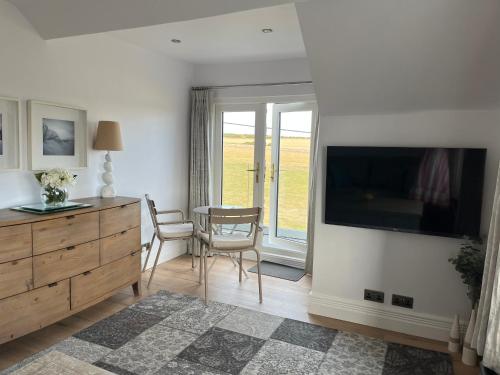 a living room with a tv and a table and chairs at Woodlands in Southerndown