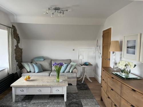 a living room with a couch and a table at Woodlands Coastal Apartment in Southerndown