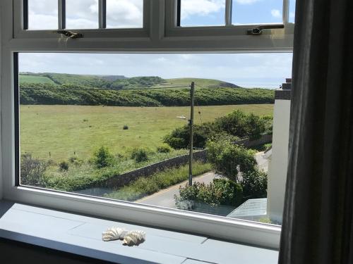 a window with a view of a field through it at Woodlands Coastal Apartment in Southerndown