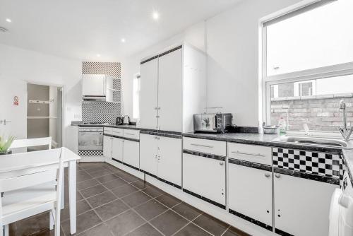 una cocina con armarios blancos y encimeras negras en Spacious Home - Ideal for Contractors en Northampton