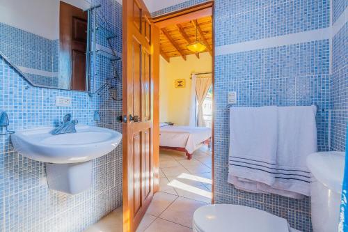 baño de azulejos azules con lavabo y aseo en D'Piero Hotel, en Sosúa