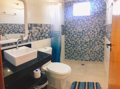 bagno con servizi igienici, lavandino e specchio di Kitnet em Imbituba - Fabi a Imbituba