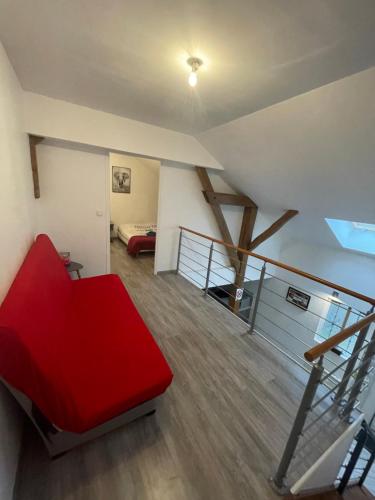 a living room with a red couch and a staircase at Le Familiale climatisé & Wi-fi in Paroy-sur-Tholon