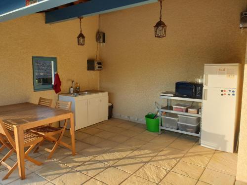 a kitchen with a table and a refrigerator at Chambres et Table d'hôtes "La Pastorale Gourmande" FR - NE - EN - DE - IT in Marcollin