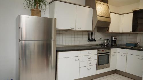 a kitchen with a stainless steel refrigerator and white cabinets at Gemütliches Apartment in Bad Berneck in Bad Berneck im Fichtelgebirge