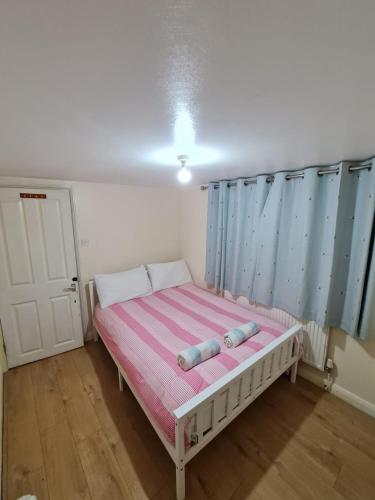 a small bedroom with a bed with a pink and blue stripes at Velvet in Whetstone