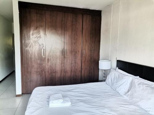 a bedroom with a large bed with a wooden door at Glammys @77 Grayston Drive in Johannesburg