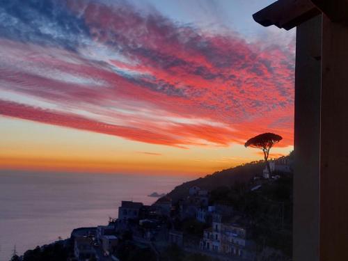 a sunset with a tree on top of a hill at San Giacomo Relais in Furore