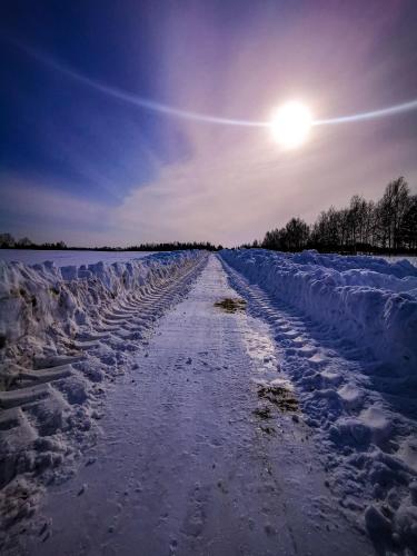 a snow covered road with the sun in the sky at Ostoja Stacze in Stacze