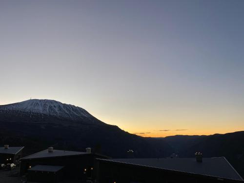 a view of a mountain at sunset with a snow covered mountain at New apartment, Gausta in Rjukan. Ski in/ ski out in Rjukan