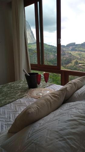two wine glasses sitting on a bed in front of a window at Apart Hotel Vista Azul - hospedagem nas montanhas in Domingos Martins