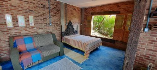 um quarto com uma cama, uma cadeira e uma janela em Casa Refúgio da Paz - 2 quartos, 10 pessoas em Conceição do Ibitipoca