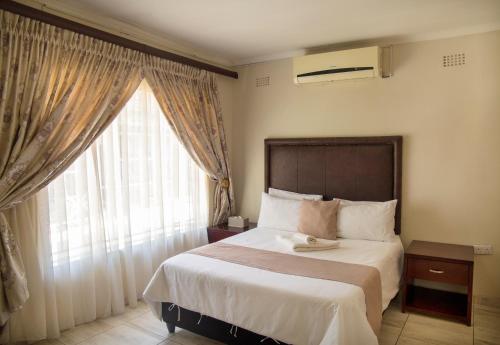a bedroom with a large bed with a large window at Haithoms Guesthouse in Gaborone
