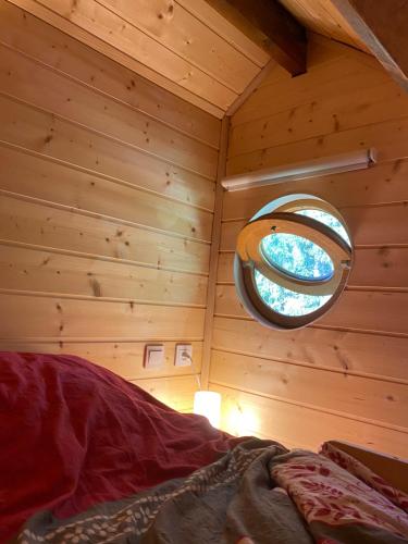 a bedroom with a round window in a log cabin at Le Paradis de Verdure in Natzwiller
