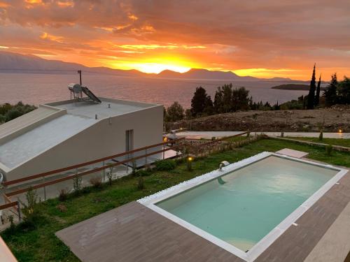 a house with a swimming pool with a sunset in the background at ANATOLI VILLAS in Nikiana