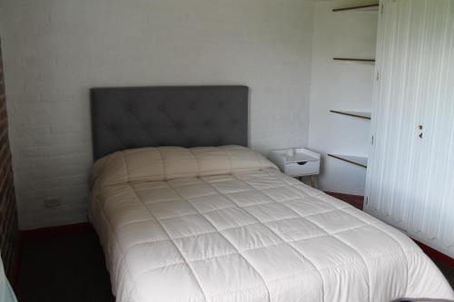 a bedroom with a white bed with a gray headboard at Villa La F in Guasca