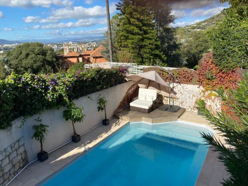 une piscine à côté d'un mur blanc avec des plantes dans l'établissement Villa Galateias, un coin de Paradis, superbe vue avec piscine privée, à Cannes