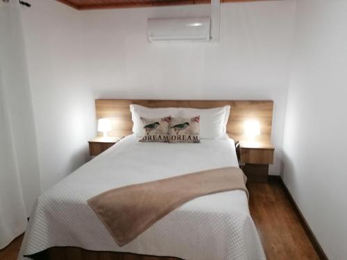a bedroom with a white bed with two lamps at A Casa da Formosinha in Madalena