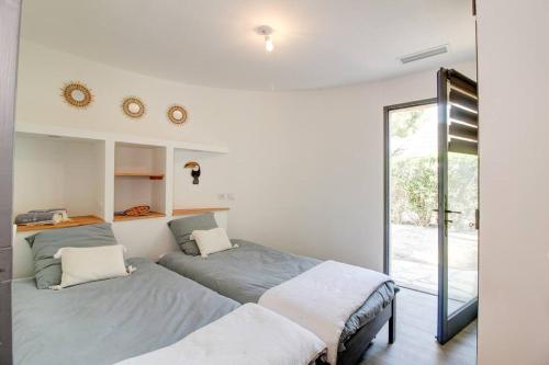deux lits dans une chambre avec une fenêtre dans l'établissement La Paillotte entre Lac Marin et Mer, au Barcarès