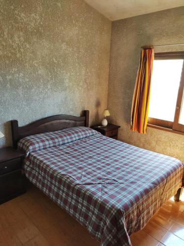 1 dormitorio con 1 cama con manta a cuadros y ventana en Casa Palazzo, en Barra del Chuy