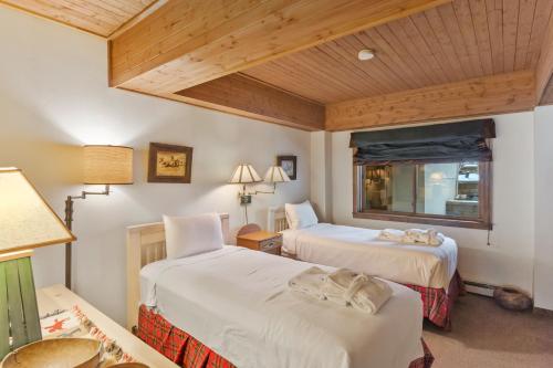 two beds in a room with wooden ceilings at Dulany 104 in Steamboat Springs