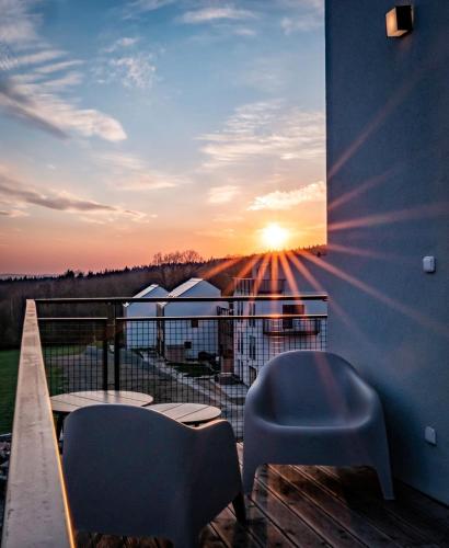 a balcony with two chairs and a view of the sunset at Apartman Eden in Rožnov pod Radhoštěm