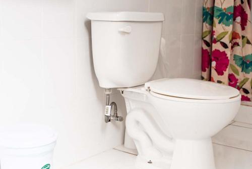 a white toilet in a bathroom with a shower curtain at Airport Beach Hotel in Montego Bay