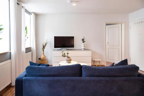 a living room with a blue couch and a tv at Elbsandstein-Suite direkt im Stadtzentrum in Pirna