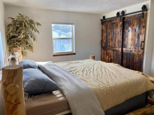 1 dormitorio con 1 cama con cabecero de madera y ventana en Cozy Mountain Home Close To Hiking, Ski &Red Rocks, en Kittredge